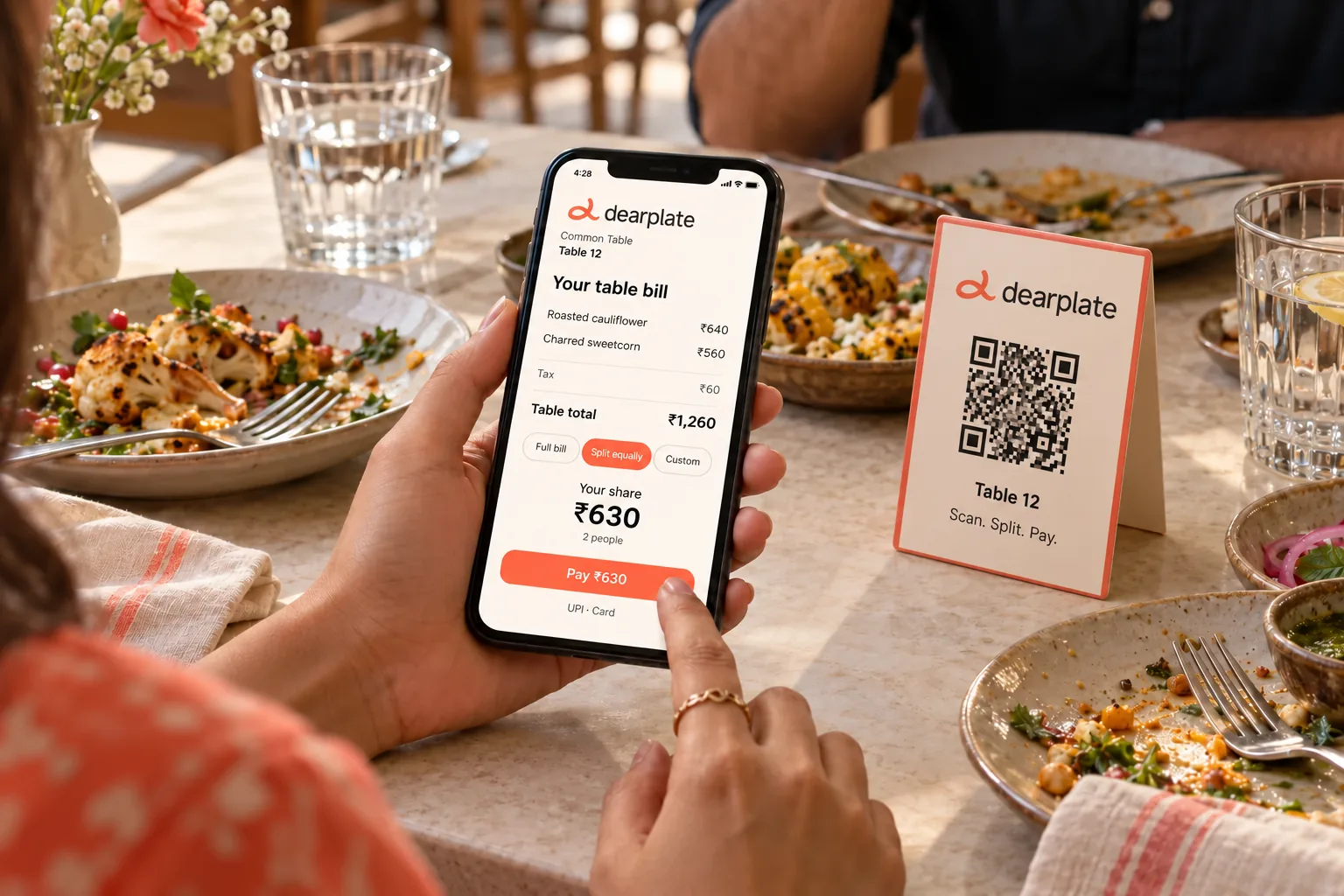 A restaurant guest viewing and splitting their Dearplate bill on a phone beside the table’s QR stand